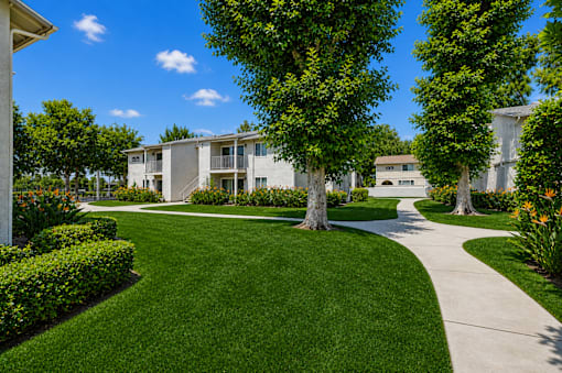 A well-maintained lawn leads to a modern apartment building.