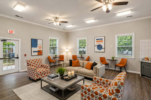 A living room with orange and white furniture and a ceiling fan.