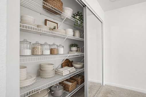 A white pantry with shelves full of dishes and containers.