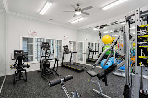 A gym with a variety of equipment including a treadmill, weights, and a bench press.