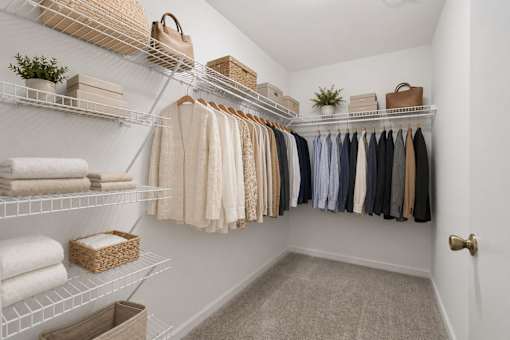 A white closet with clothes and towels on shelves.