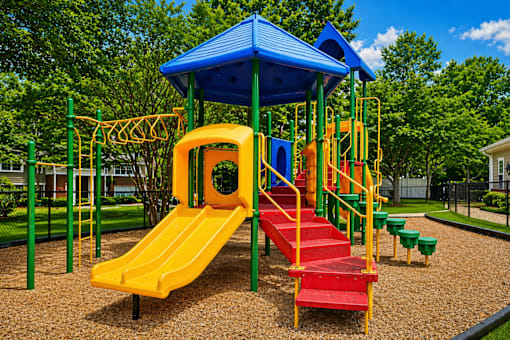 A playground with a yellow slide and a blue roof.