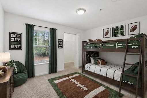 A room with a bunk bed and a football themed rug.
