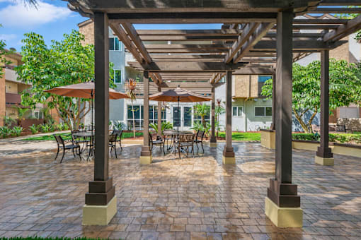 A patio with a table and chairs under a wooden pergola.