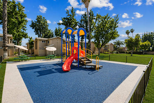A playground with a red slide and a blue and yellow structure.