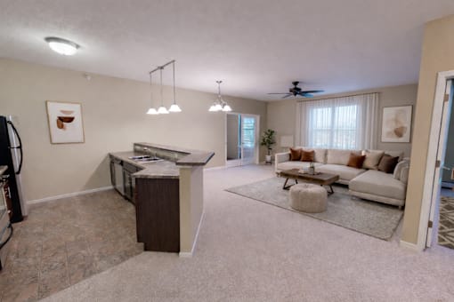 Kitchen island overlooking furnished living room at The Ponds at Heritage Place Apartments, Sartell, MN