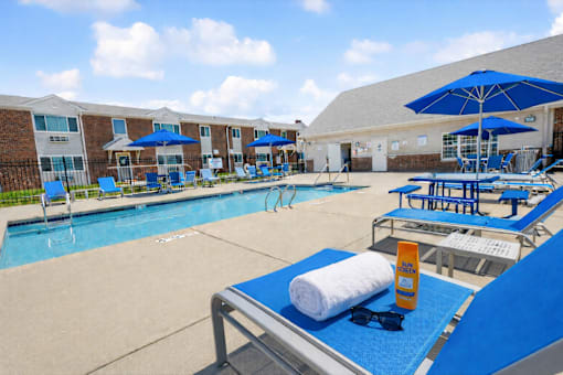 A sunny day at the pool with blue loungers and umbrellas.