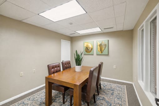 A conference room with a table, chairs, and two framed pictures on the wall.