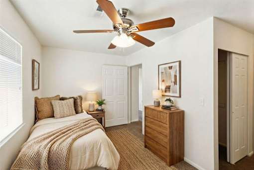 A bedroom with a bed, nightstand, and a ceiling fan.