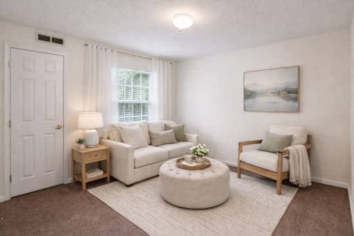 A living room with a white couch, a white chair, and a white ottoman.