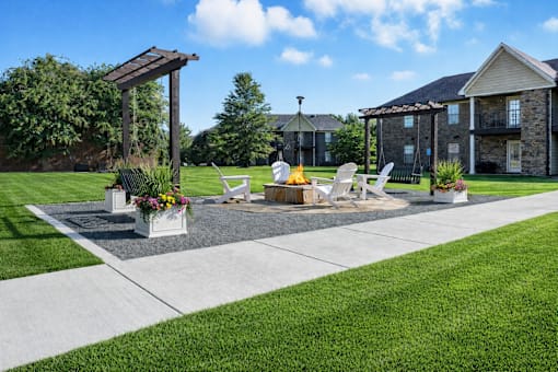 A patio with a table and chairs is surrounded by a grassy area.