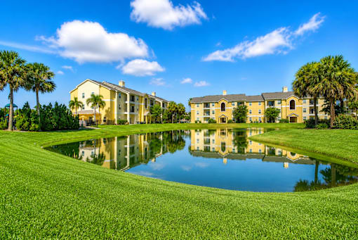 A large building is reflected in a pond in front of it.