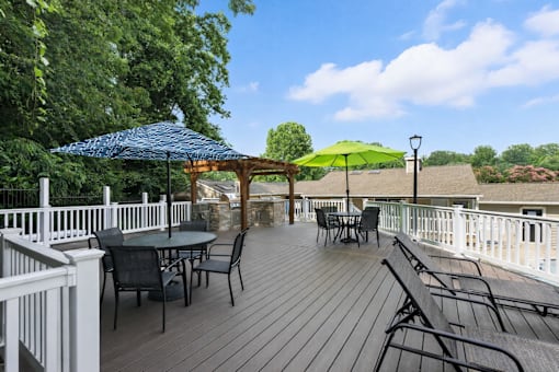 A wooden deck with a table and chairs and umbrellas.