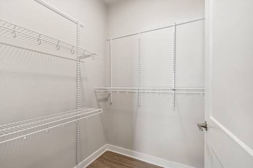 A white walk in closet with shelves and hooks.