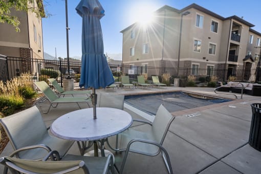 our apartments have a pool and a patio with chairs and an umbrella