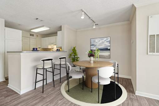 A kitchen with a bar and a dining table with chairs.