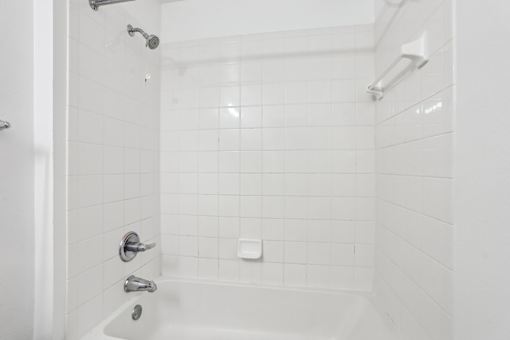 A white bathroom with a white tub and white tiles.