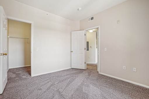 A room with a carpeted floor and two doors.