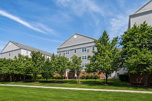 A large building with a grey roof is surrounded by trees.