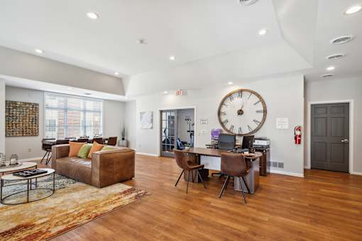 A large room with a brown couch and a large clock on the wall.