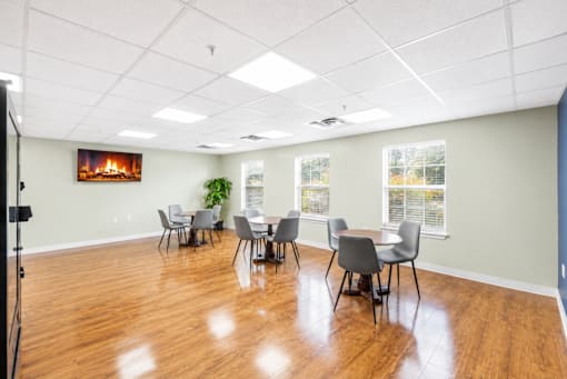 A room with a table and chairs and a fireplace in the background.