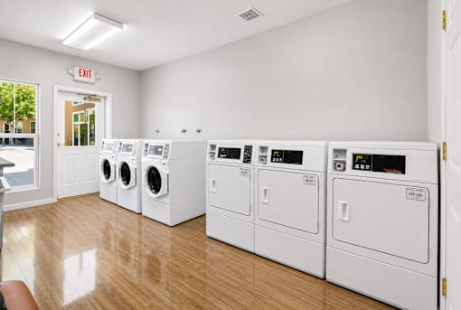A row of white front load washing machines in a laundromat.