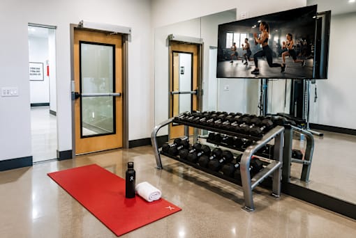 A gym room with a television showing a fitness class.