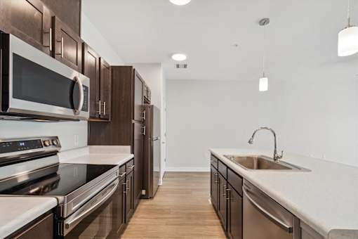A modern kitchen with dark wood cabinets and stainless steel appliances.