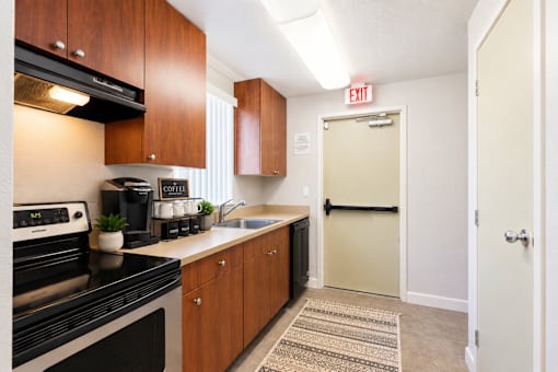A kitchen with a black stove top oven and wooden cabinets.