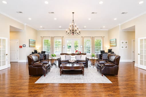 A large, well-lit living room with a chandelier, a coffee table, and leather furniture.