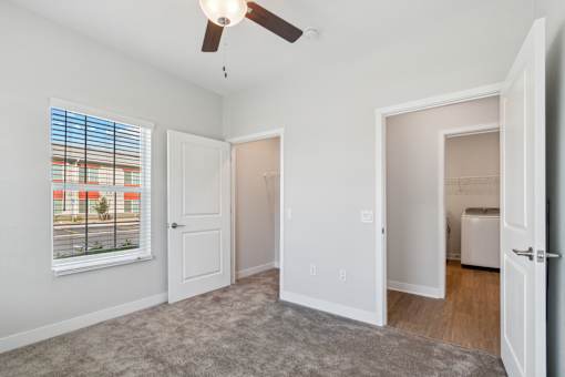 A room with a ceiling fan and a window with blinds.