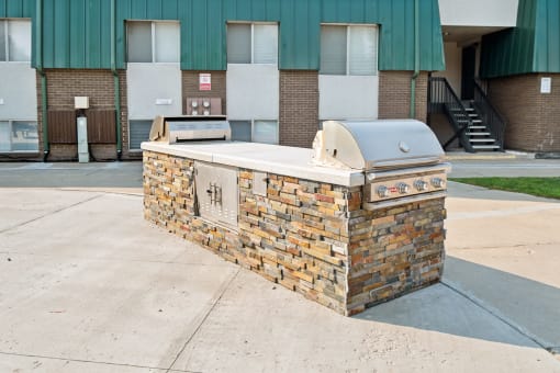 an outdoor grill with a building in the background
