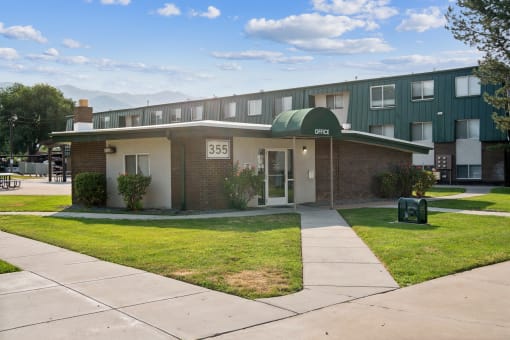 an apartment building with a green roof and a sidewalk