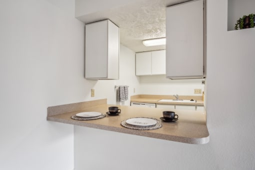 a kitchen with white cabinets and a counter with plates and mugs