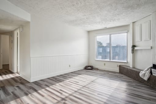 an empty living room with wood floors and a window