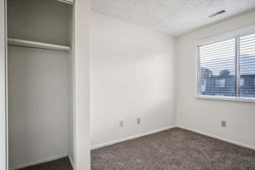 an empty bedroom with a window and a closet