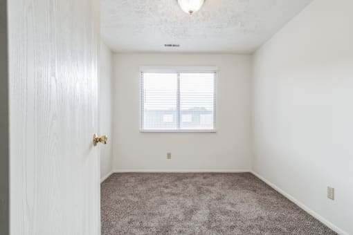 an empty bedroom with carpet and a window