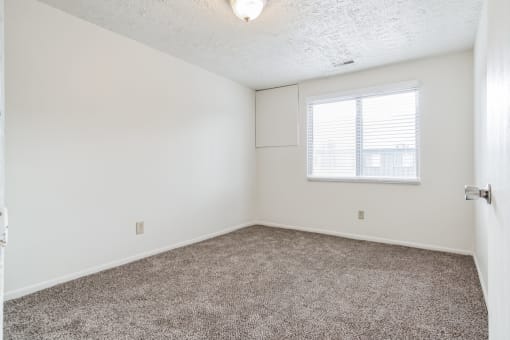 an empty room with carpet and a window