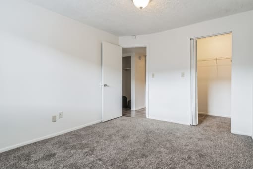 an empty bedroom with white walls and a door to a closet