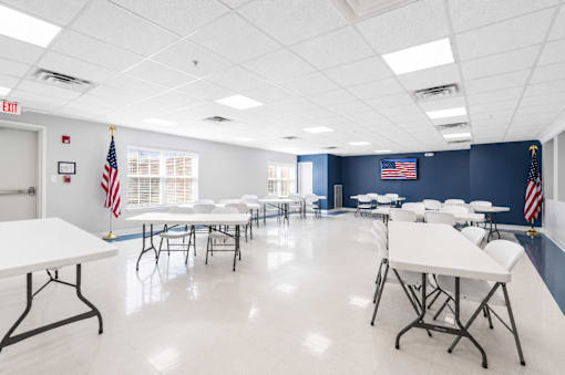 A room with tables and chairs and flags on the wall.