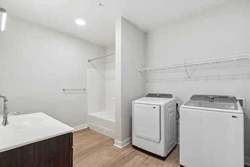 A white bathroom with a sink, toilet, and washer.