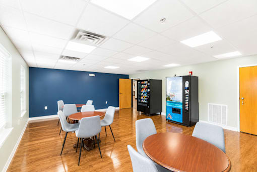 A conference room with a table, chairs, and a vending machine.