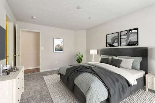 A bedroom with a large bed and a nightstand with a lamp.