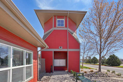 A red house with a white roof and a green bench in front.