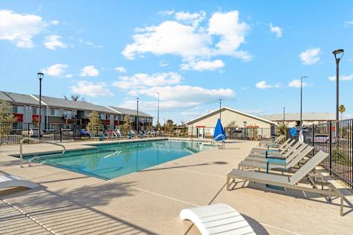 A sunny day at the pool with lounge chairs and a clear blue sky.