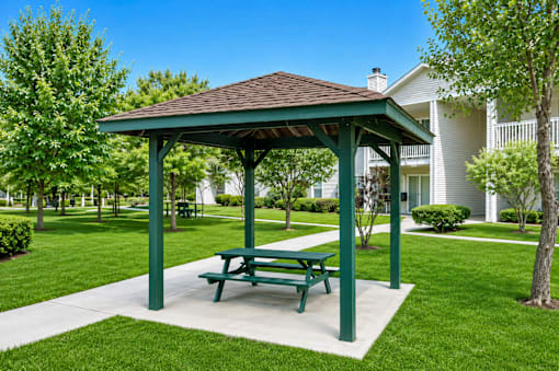 A green picnic table is in the middle of a grassy area.