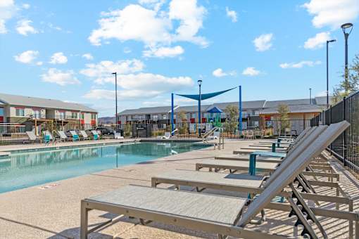 A sunny day at the pool with lounge chairs and a play area.