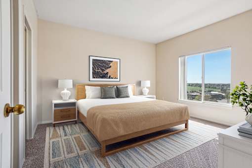 A bedroom with a bed, nightstands, and a window overlooking a landscape.
