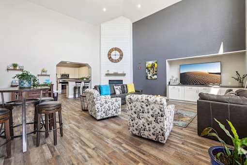 A living room with a grey couch and a white wall with a clock on it.