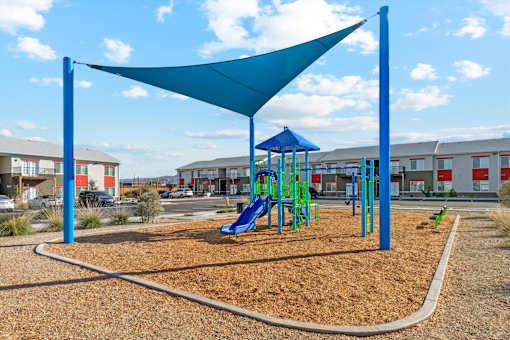 A playground with a blue shade structure and a green slide.